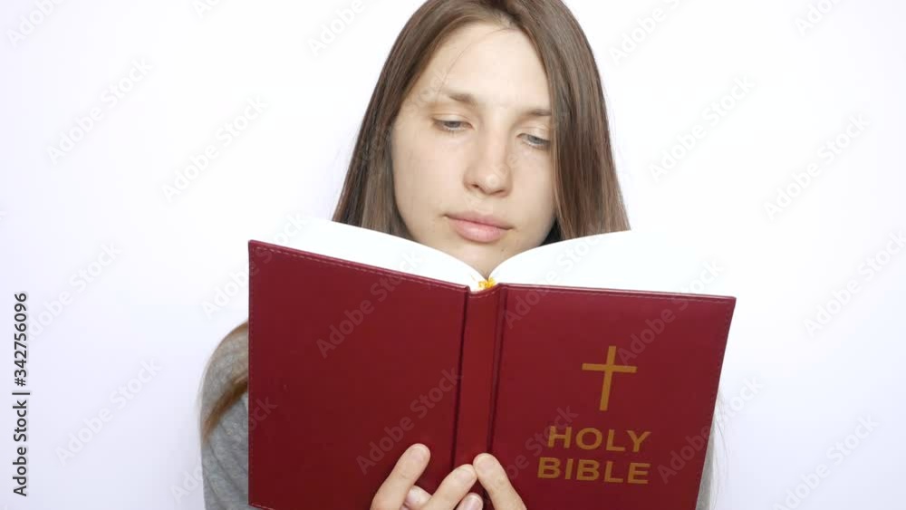A young beautiful woman reads the Holy Bible carefully A young beautiful woman reads the Holy Bible carefully