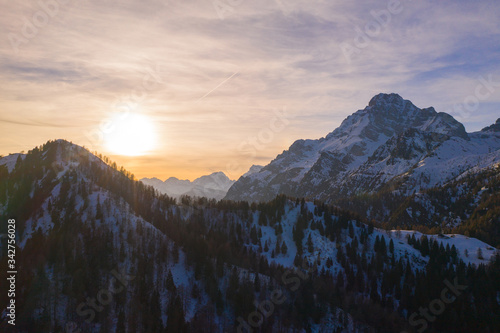 sun behind thin clouds on snowy mountains of dolomites