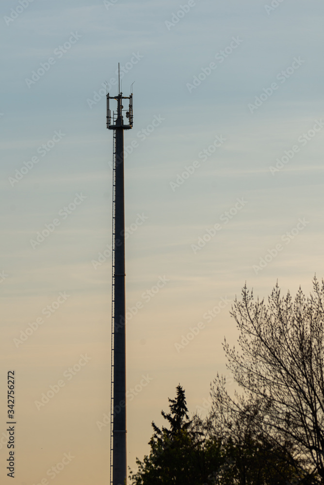 Telecommunication tower with cellular network antenna against blue sky as background