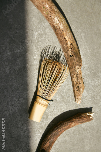 Bamboo whisk for matcha tea and wooden sticks on a gray background.