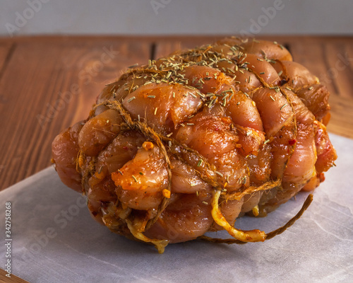 Chicken breast ham baking blanket tied with twine with spices on a cutting marble board