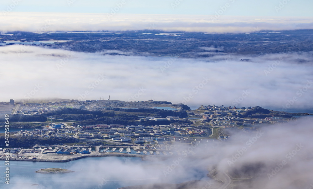 New Nuuk city, capital of Greenland photographed from mountaintop, through clouds background