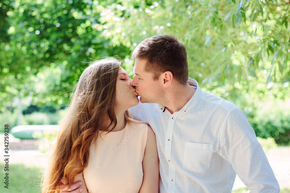Fototapeta premium Young couple - girl and guy kissing at the park