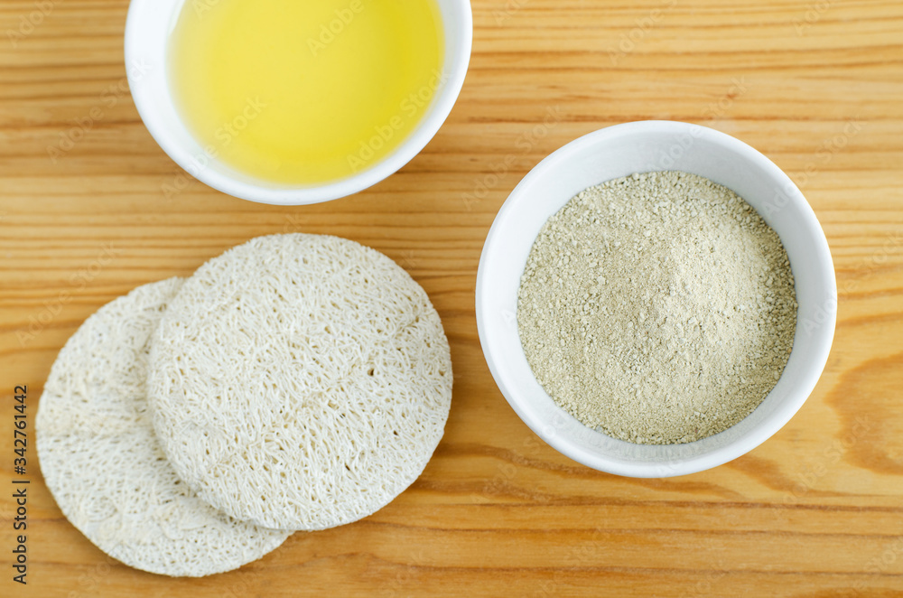 Kaolin clay powder in tha small white bowl and loofah sponges. Clay texture close up. Diy facial or hair mask, dry shampoo recipe. Natural beauty treatment and spa. Top view, copy space Kaolin clay powder in tha small white bowl and loofah sponges. Clay texture close up. Diy facial or hair mask, dry shampoo recipe. Natural beauty treatment and spa. Top view, copy space