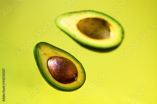Bright background with halves of fresh avocado in the air. Diet and healthy diet. Exotic of berry.