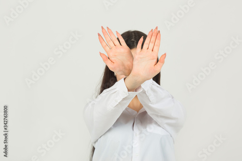 beautiful young woman in a white shirt on a white background with hand gesture 