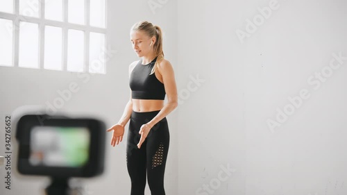 Fit and healthy young woman does stretch or yoga pilates workout on camera. Live stream of fitness instructor work from home. Stay fit with home bodyweight routine photo