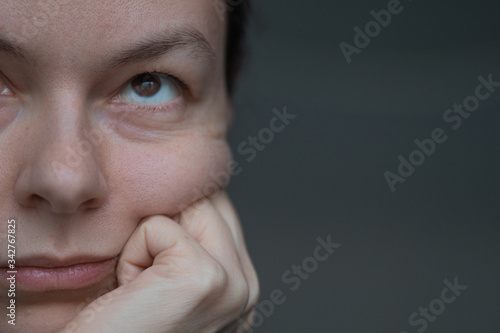 A bored woman rests her cheek on her hand, the creases