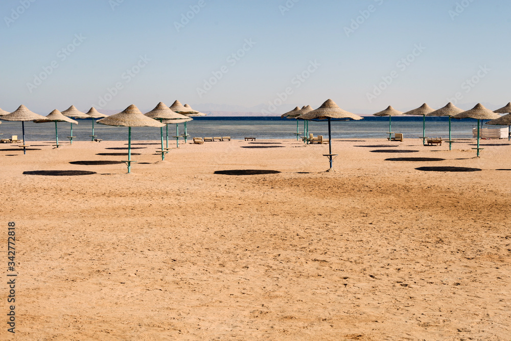 empty beach at summer time. empty matching umbrellas on a beach, blue skies in the distant view. Horizontal with copy space.