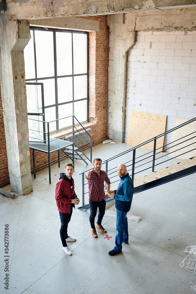 Group of young engineers or contractors having meeting by staircase Group of young engineers or contractors having meeting by staircase