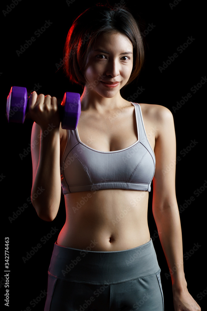Young woman in gray sportswear exercise at home, doing lifting dumbbells, in quarantine during Coronavirus pandemic. Young woman in gray sportswear exercise at home, doing lifting dumbbells, in quarantine during Coronavirus pandemic.