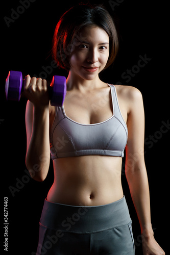 Young woman in gray sportswear exercise at home, doing lifting dumbbells, in quarantine during Coronavirus pandemic.
