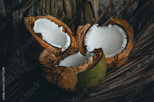 Broken coconuts on a wooden table with palm leaves