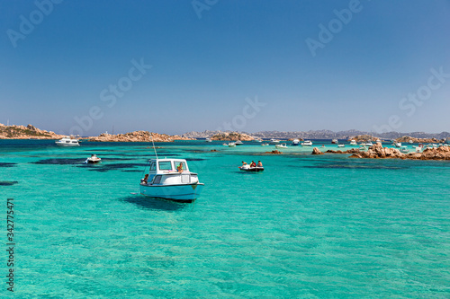 Various tourist boats are stationed in the clear and transparent waters in the Maddalena archipelago in Sardinia, Italy.