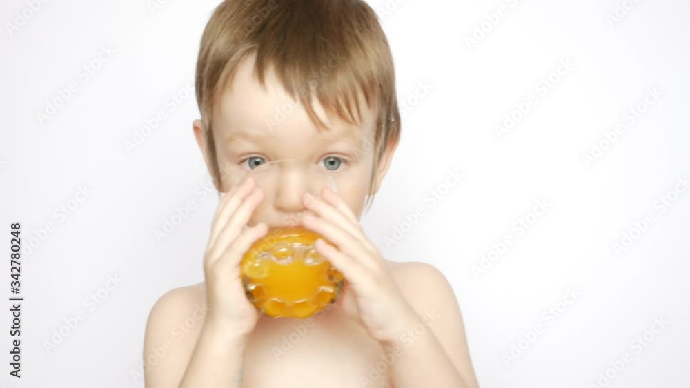 A very beautiful naked boy drinks fresh orange juice from a glass A very beautiful naked boy drinks fresh orange juice from a glass