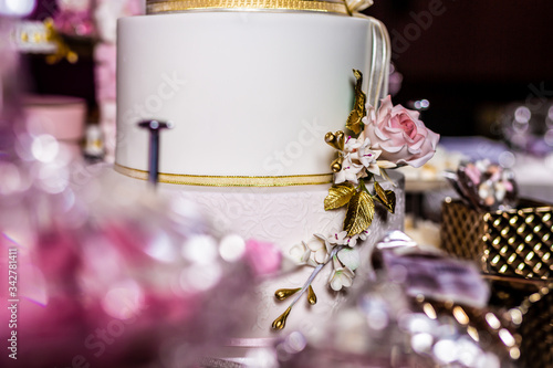 Closeup of a red, pink, and white flower on a wedding cake with gold and silver.