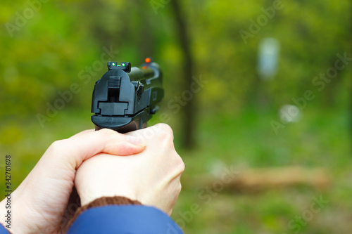 The girl holds a gun in her hands and aims.
