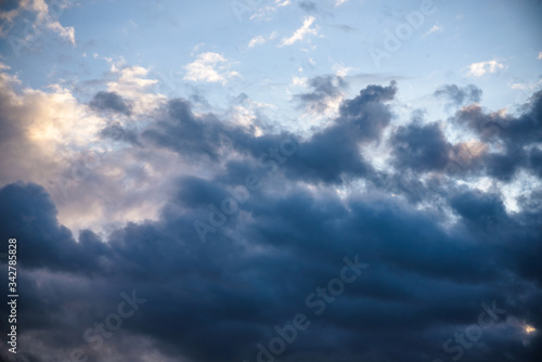 CLOSE UP: Dark grey stormy clouds gather above Lake Maggiore on a calm summer evening. Dramatic shot of clouds covering up the colorful sunlit morning sky. Orange hued evening sky and stormy clouds.