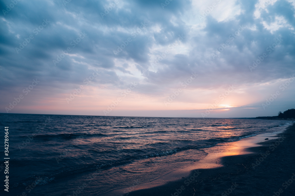 Photo of the gulf of finland at sunset. Violet sky at sunset. Sea beach.