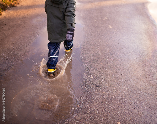 child jumps into a puddle in which the sky is reflected