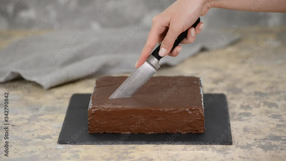 Female hand cutting chocolate cake with knife. Female hand cutting chocolate cake with knife.