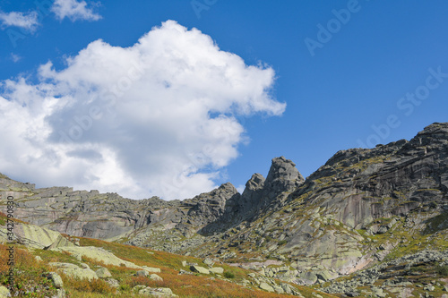 rocky ridge under blue sky in mountain valley, journey of climbers on sheer cliffs