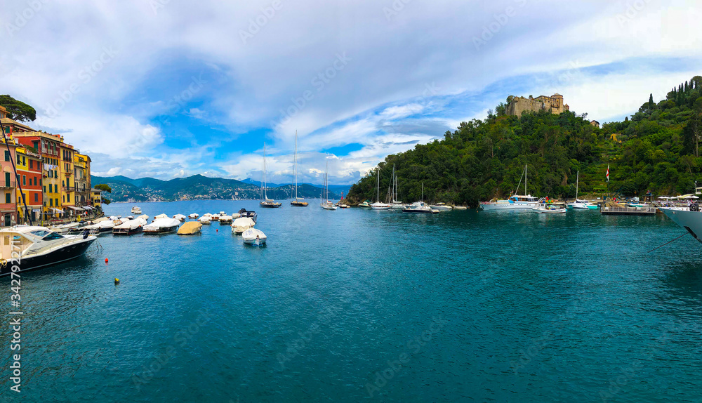 Naklejka premium Wide panoramic view of Portofino, one of the world's most beautiful seaside towns on the Italian Riviera. Mediterranean landscape of yacht-filled harbor. ITALY - June, 2018.