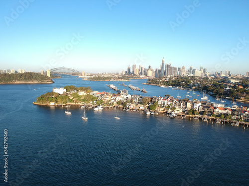 Panoramic drone aerial view over Sydney harbour on a cloudy sunset showing the nice colours of the harbour foreshore © Elias Bitar
