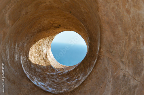 Sea view through the stone hole. Watch blue sky and sea through the stone spiral tunnel in Cyprus