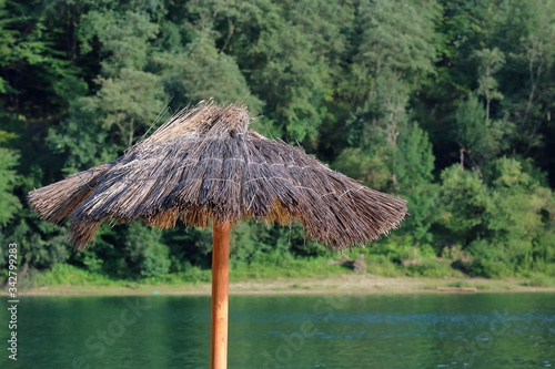 reed beach umbrella close up  in background sea lake and green forest  concept of tourism close to nature 