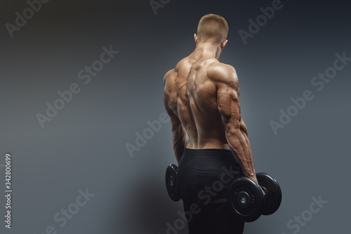 Obraz na płótnie Handsome athlete training biceps with dumbbells