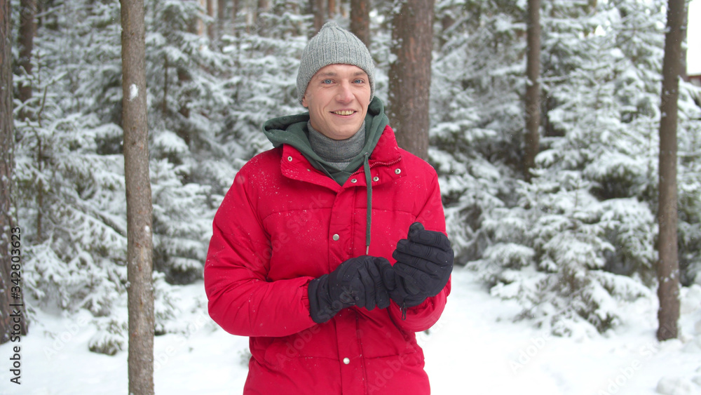Fototapeta premium A man in a snowy forest puts on winter gloves