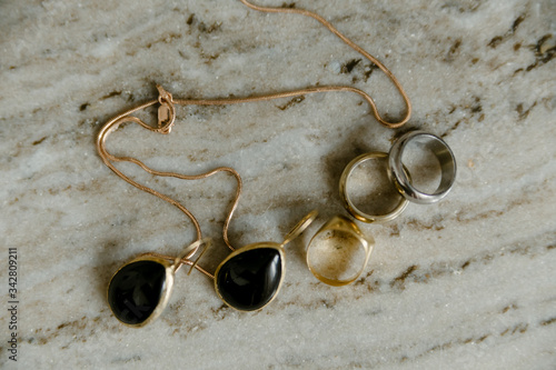 black pearl earrings jewelry in a gold frameand gold and silver rings on a marble table background photo