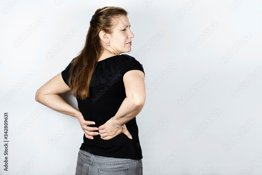 The woman is holding her back because she is experiencing severe lower back pain. The woman cleaned the house and did not get up well The woman is holding her back because she is experiencing severe lower back pain. The woman cleaned the house and did not get up well