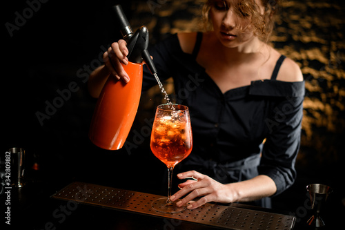 woman bartender pour liquid from orange siphon to glass with bright drink