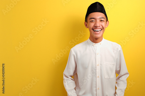 Fotografija Smiling Young Asian Muslim man standing over yellow