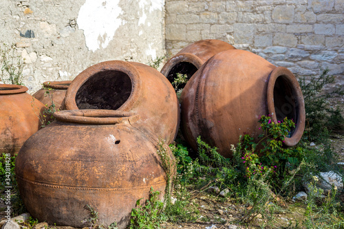 Large brown earthenware jars lie against the wall. Cyprus, Omodos village. Potteries vessels