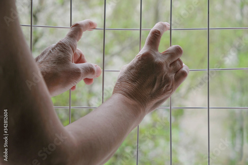 Lady's hands on a metal grid. Imprisonment concept. Copy space. Minimalism. 