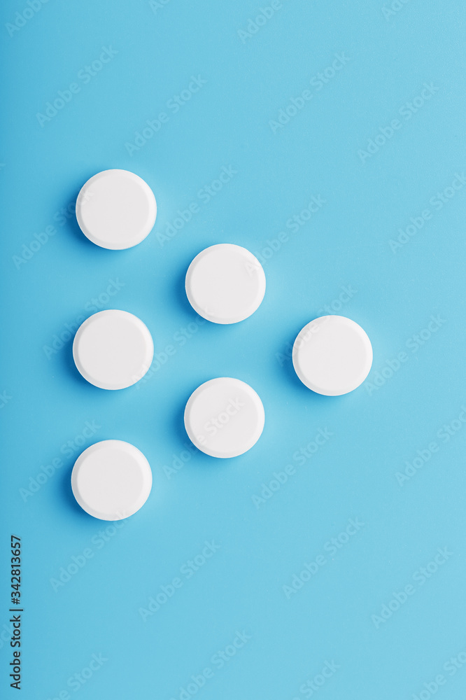 Round medicinal tablets in the shape of a triangle on a blue background, isolate. Round medicinal tablets in the shape of a triangle on a blue background, isolate.