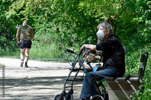 seniorin mit atemschutzmaske sitzt in einem park
