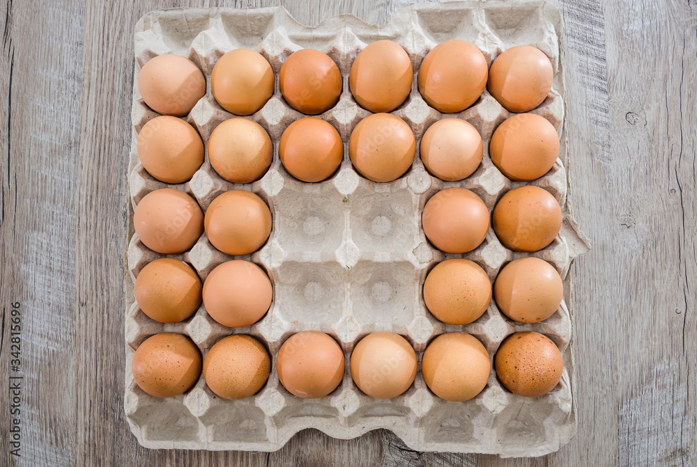 Chicken eggs in a cardboard box on a wooden table without four eggs. Chicken eggs in a cardboard box on a wooden table without four eggs.