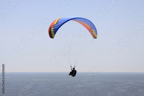a man hovering in the air on a paraglider above the sea