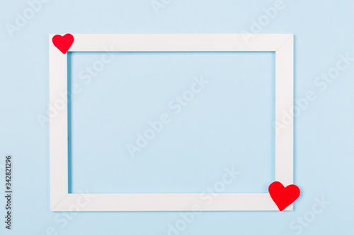 White frame empty blank picture with red heart on light blue background . Copy space free text. Holiday card concept. Mock up. Greeting. Mother's Day. St Valentine's Day. Love . Wedding invitation. 