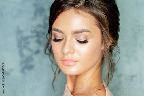 Portrait of woman with makeup and long eyelashes on gray background.