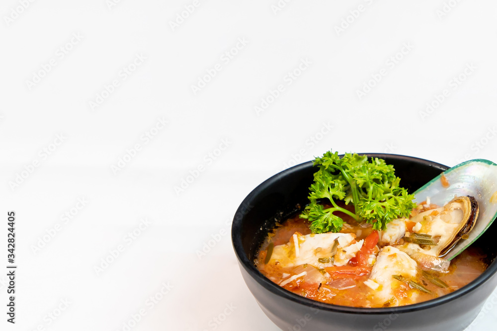 Italian seafood soup in a black cup on a white background