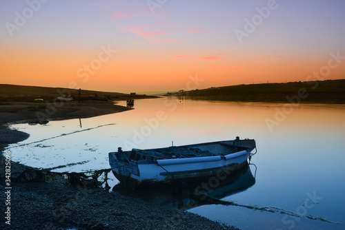 Fototapeta Naklejka Na Ścianę i Meble -  Moored boat on Chesil Beach at sunset