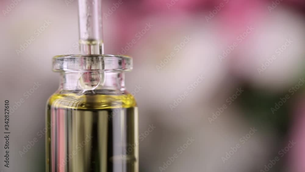 Blend of essential oils closeup. Making some aroma liquids, perfume. Drops falling from pippet to little glass bottle. Slowmotion. Liquid ingredients, body care production, cosmetology. Blend of essential oils closeup. Making some aroma liquids, perfume. Drops falling from pippet to little glass bottle. Slowmotion. Liquid ingredients, body care production, cosmetology.