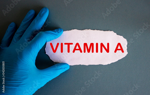 Hand in blue glove with white small paper. Concept word vitamin A. photo