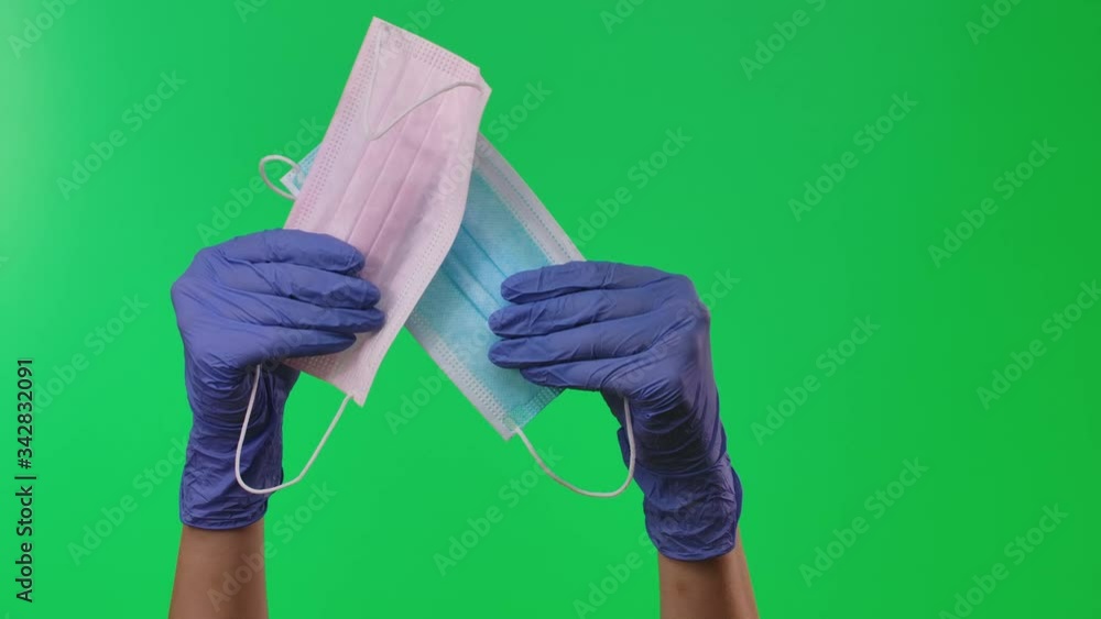 Doctor showing respiratory face masks holding equipment in his hands protected by blue medical gloves. Green screen. Close up. Doctor showing respiratory face masks holding equipment in his hands protected by blue medical gloves. Green screen. Close up.
