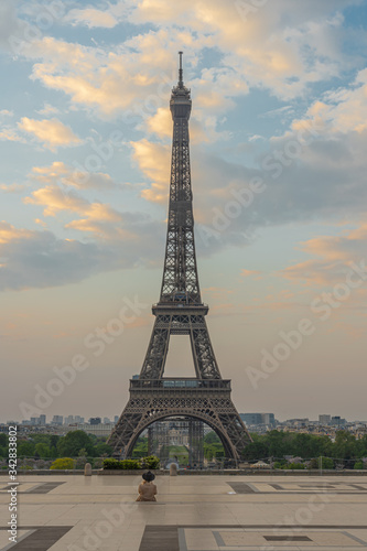 Paris, France - 04 25 2020: View of the Eiffel Tower from the Trocadero esplanade with a seatead woman during the coronavirus period